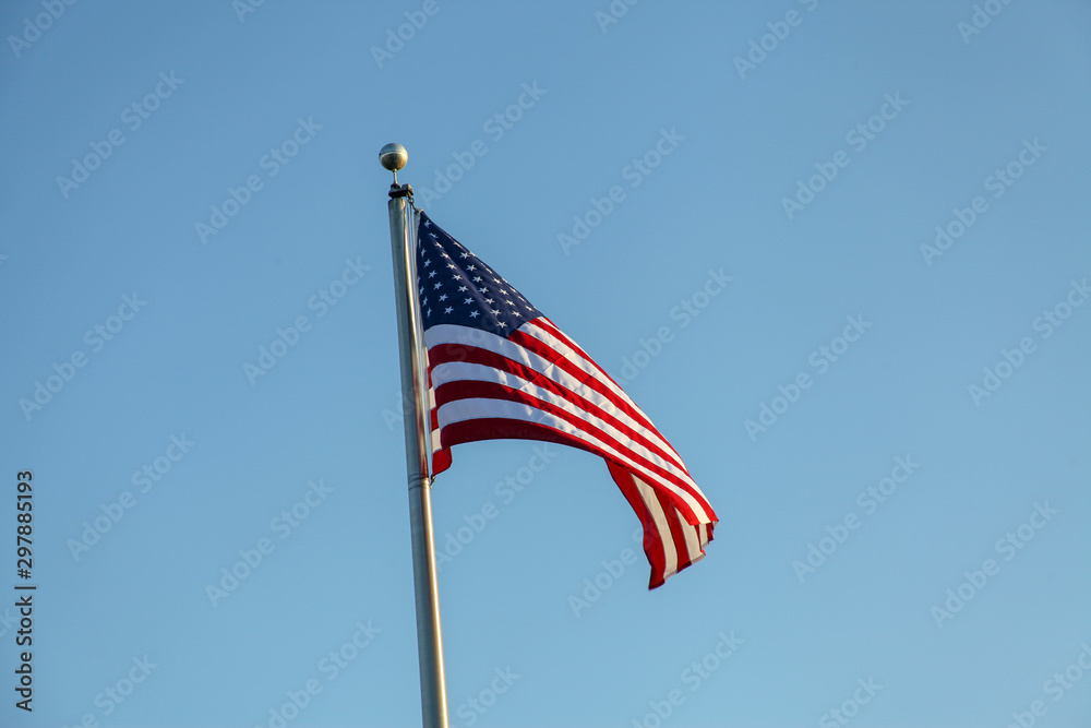 Flag of United States of America, photographed in the wind, fluttering, consisting of 7 red and 6 white bands and a blue rectangle with 50 stars, symbolizing the states of the country.