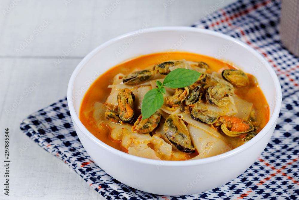 Coconut Milk Curry with bamboo shoot and green mussel in bowl on wood table Coconut Milk Curry with bamboo shoot and green mussel in bowl on wood table
