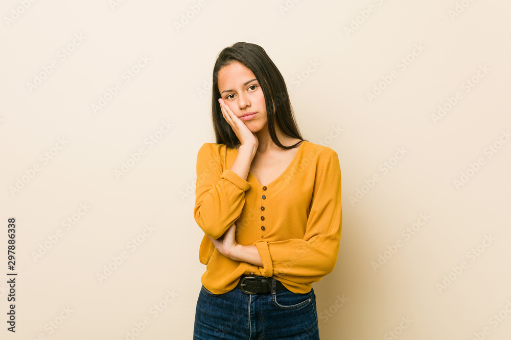 Young hispanic woman against a beige background who is bored, fatigued and need a relax day. Young hispanic woman against a beige background who is bored, fatigued and need a relax day.
