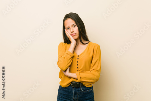 Young hispanic woman against a beige background who is bored, fatigued and need a relax day.