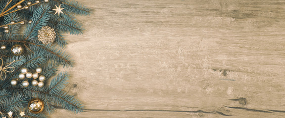 Christmas background with decorated fir tree branch border on vintage wood, flat lay, panoramic toned image