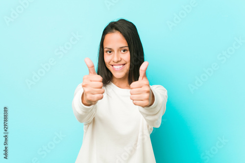 Young pretty hispanic woman with thumbs ups, cheers about something, support and respect concept. photo