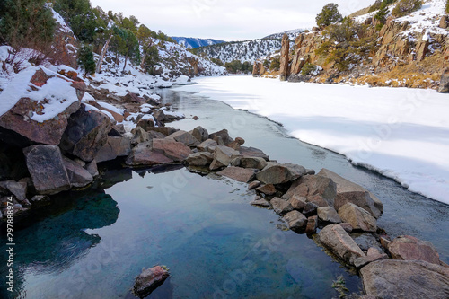 CLOSE UP: Picturesque view of a natural hot bath overlooking snowy landscape. photo