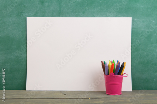 colored crayons on wooden table - elementary school education concept, chalkboard background