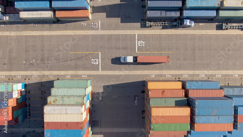 TOP DOWN: White truck transports a red freight container across the busy port. photo