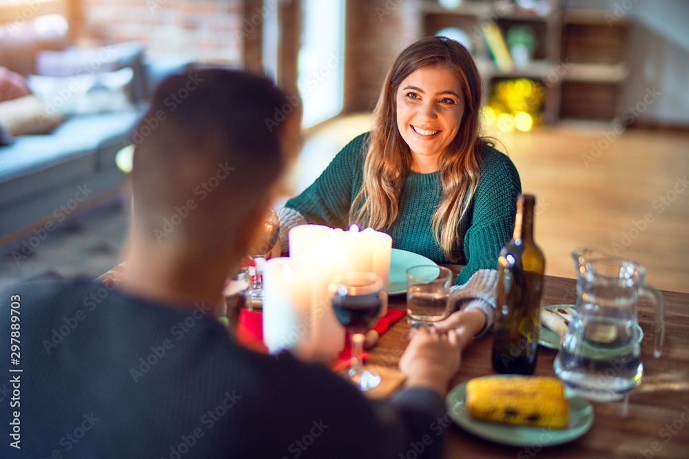 Young beautiful couple smiling happy and confident. Eating food celebrating christmas at home