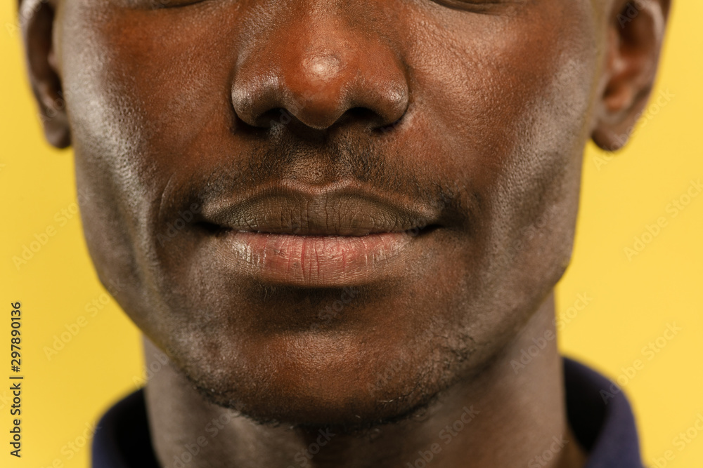 African-american young man's close up portrait on yellow studio background. Beautiful male model with well-kept skin. Concept of human emotions, facial expression, sales, ad. Looks calm and smiling. African-american young man's close up portrait on yellow studio background. Beautiful male model with well-kept skin. Concept of human emotions, facial expression, sales, ad. Looks calm and smiling.