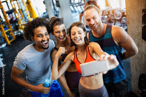 Fototapeta Naklejka Na Ścianę i Meble -  Group of sportive people in a gym taking selfie. Concepts about lifestyle and sport in fitness club
