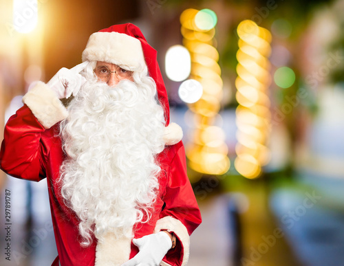 Middle age handsome man wearing Santa Claus costume and beard standing Smiling pointing to head with one finger, great idea or thought, good memory