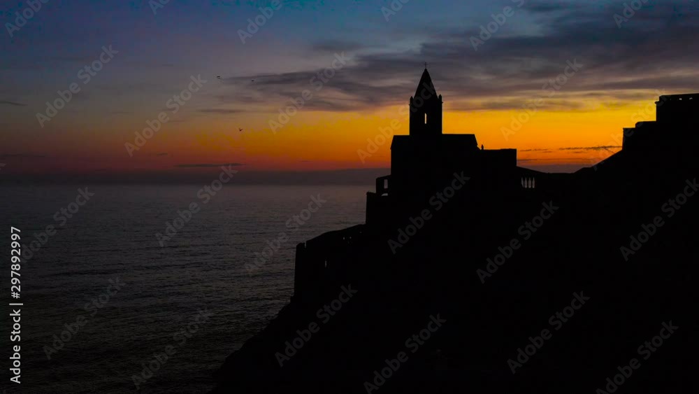 aerial tracking zoom in with a drone flying over the church of San Pietro in Portovenere seen from the land side with a silhouette silhouetted against the sunset aerial tracking zoom in with a drone flying over the church of San Pietro in Portovenere seen from the land side with a silhouette silhouetted against the sunset