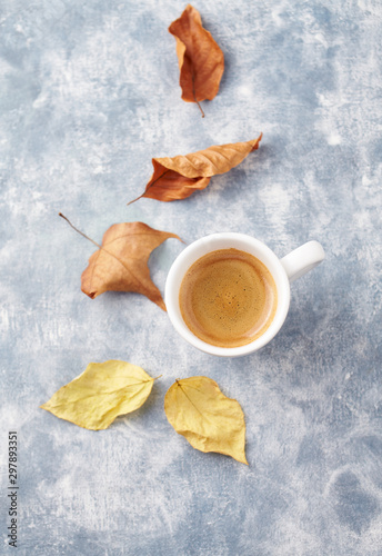 Cup of coffee and autumn leaves. Bright wooden background. Top view. Copy space. 