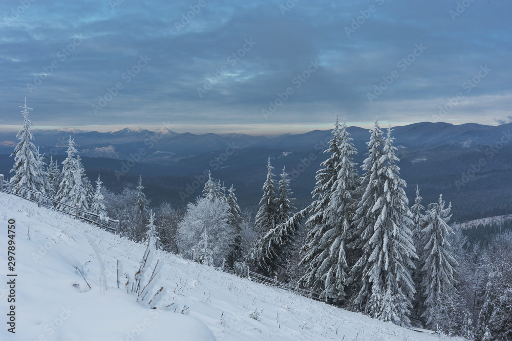 Fototapeta premium Magic winter fogs in Ukrainian Carpathians overlooking the snow-capped mountain peaks from the picturesque mountain valley with tourists in tents.