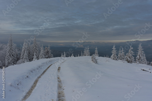 Magic winter fogs in Ukrainian Carpathians overlooking the snow-capped mountain peaks from the picturesque mountain valley with tourists in tents.