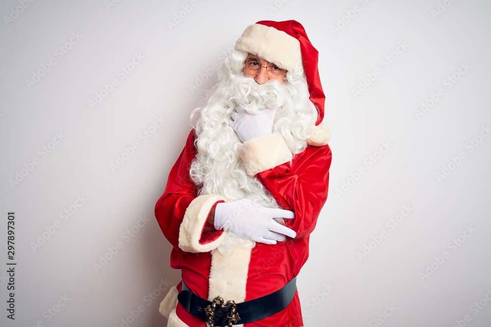 Middle age handsome man wearing Santa costume standing over isolated white background looking confident at the camera smiling with crossed arms and hand raised on chin. Thinking positive.