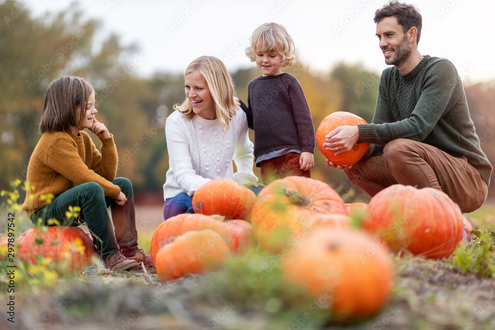 Fototapeta premium Happy young family in pumpkin patch field
