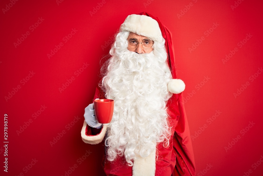 Senior man wearing Santa Claus costume holding cup of coffee over isolated red background with a confident expression on smart face thinking serious