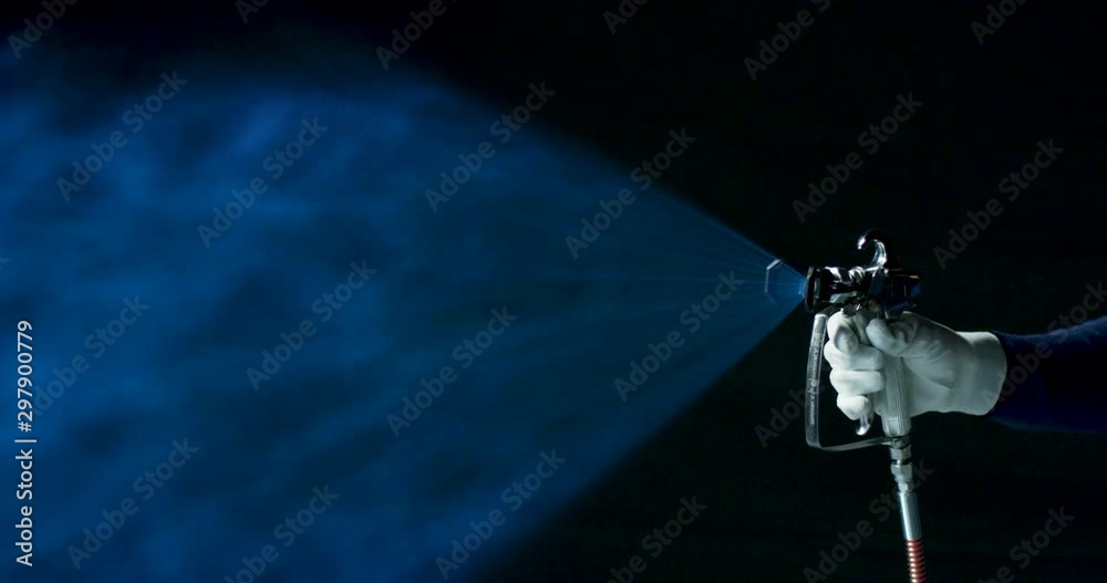 Worker using high pressure spray gun with blue dye slow motion