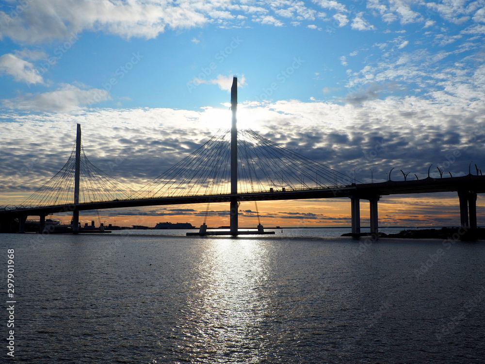 modern suspension road bridge over the bay against the setting sun