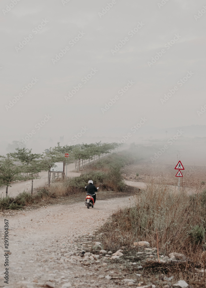 Biker entering to check the plantation field covered by morning fog Biker entering to check the plantation field covered by morning fog