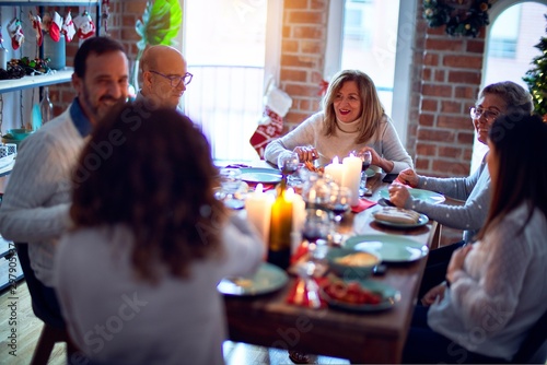 Family and friends dining at home celebrating christmas eve with traditional food and decoration, all sitting on the table together