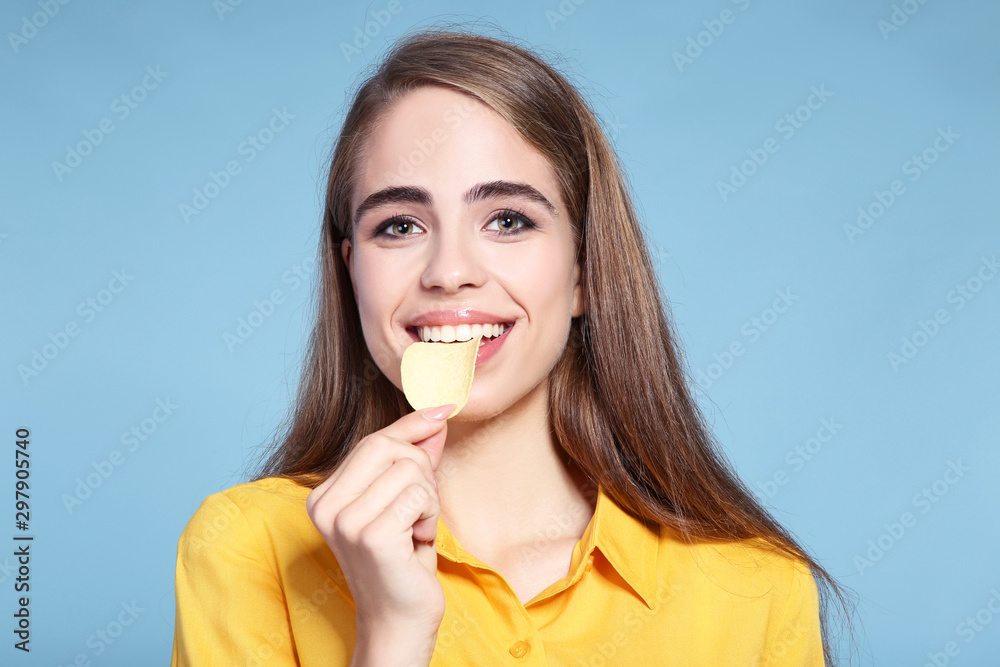 Young beautiful girl eating potato chip on blue background Young beautiful girl eating potato chip on blue background