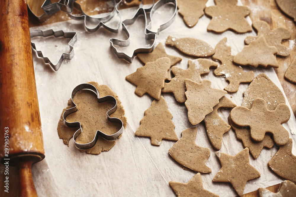 Making christmas gingerbread man cookies. Raw dough in shape of tree and man and metal cutters, wooden rolling pin, anise, ginger, cinnamon, pine cones, fir branches on rustic table. Making christmas gingerbread man cookies. Raw dough in shape of tree and man and metal cutters, wooden rolling pin, anise, ginger, cinnamon, pine cones, fir branches on rustic table.