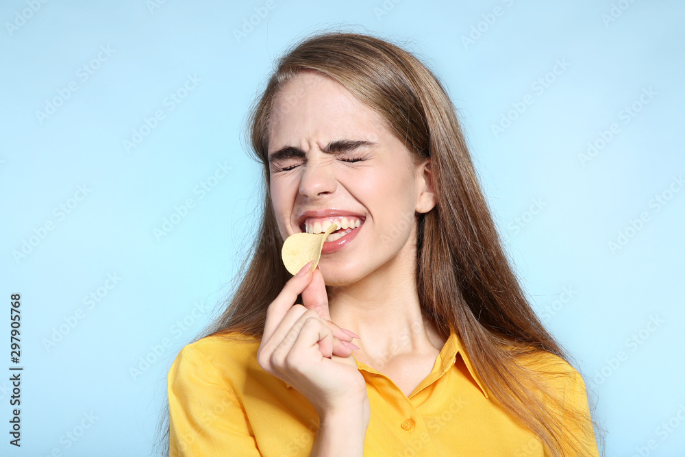 Young beautiful girl eating potato chip on blue background Young beautiful girl eating potato chip on blue background