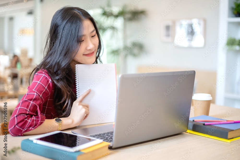 Young Asian woman using laptop computer and tablet PC to working in the modern co working space Young Asian woman using laptop computer and tablet PC to working in the modern co working space