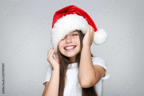 Obraz na płótnie Little girl in christmas hat on grey background w salonie