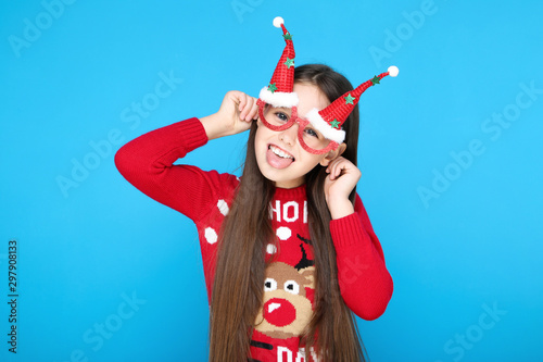 Little girl in sweater and christmas eyeglasses on blue background