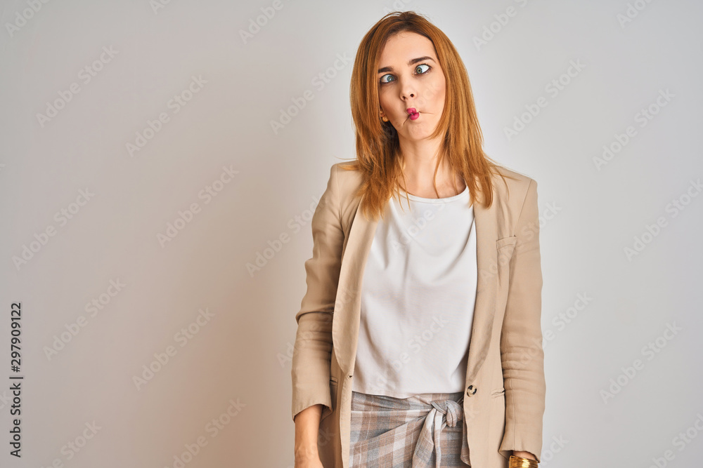 Redhead caucasian business woman standing over isolated background making fish face with lips, crazy and comical gesture. Funny expression. Redhead caucasian business woman standing over isolated background making fish face with lips, crazy and comical gesture. Funny expression.