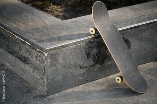 View of black skateboard in concrete skatepark on warm day photo