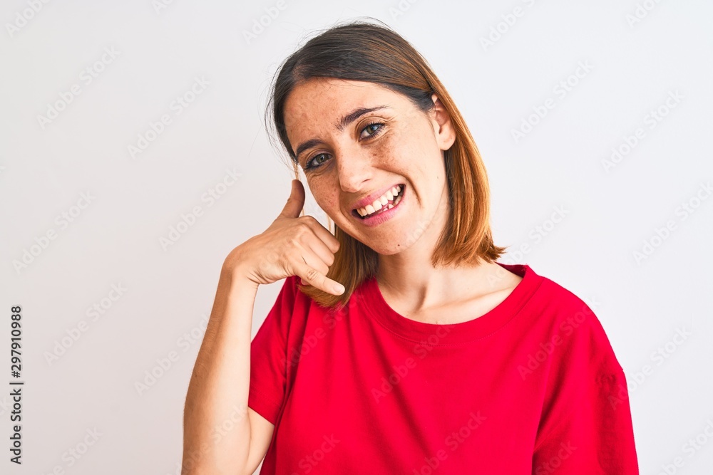 Beautiful redhead woman wearing casual red t-shirt over isolated background smiling doing phone gesture with hand and fingers like talking on the telephone. Communicating concepts. Beautiful redhead woman wearing casual red t-shirt over isolated background smiling doing phone gesture with hand and fingers like talking on the telephone. Communicating concepts.