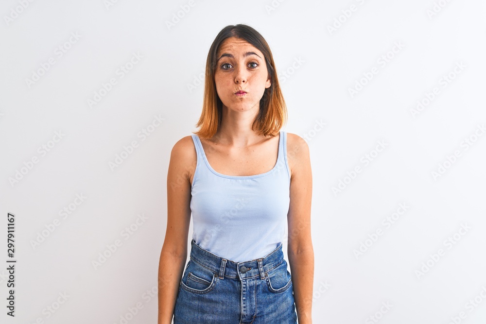 Beautiful redhead woman standing over isolated background puffing cheeks with funny face. Mouth inflated with air, crazy expression. Beautiful redhead woman standing over isolated background puffing cheeks with funny face. Mouth inflated with air, crazy expression.