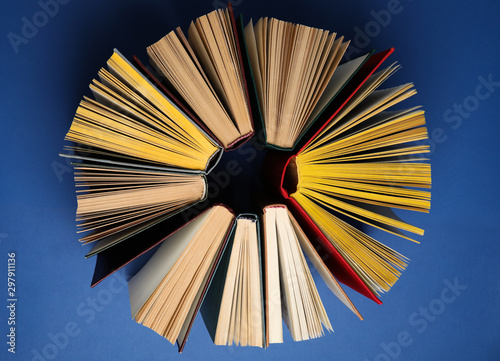 Circle made of hardcover books on blue background  flat lay