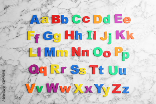 Colorful magnetic letters on white marble background, flat lay. Alphabetical order