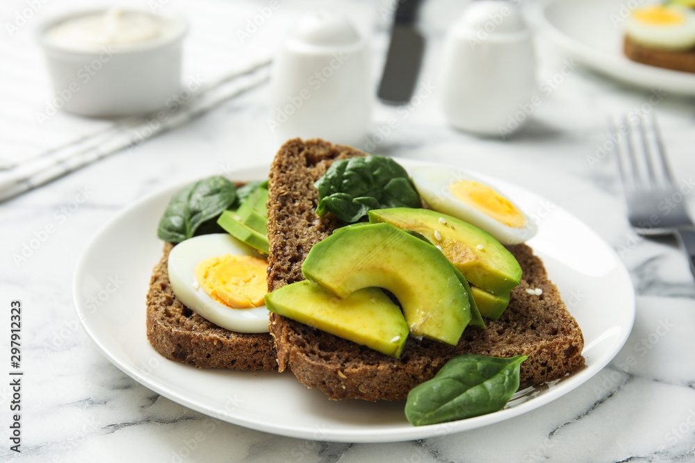 Tasty avocado toasts with quail egg on white marble table