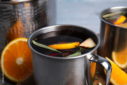 Tasty mulled wine with spices in mug on table, closeup
