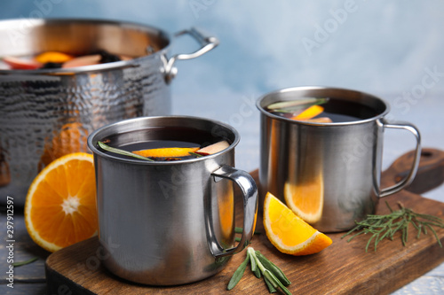 Tasty mulled wine with spices in mugs on wooden table