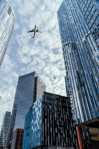Generic airplane flying over glass skyscrapers