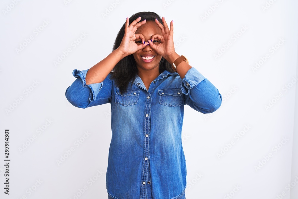 Beautiful young african american woman wearing denim jacket over isolated background doing ok gesture like binoculars sticking tongue out, eyes looking through fingers. Crazy expression. Beautiful young african american woman wearing denim jacket over isolated background doing ok gesture like binoculars sticking tongue out, eyes looking through fingers. Crazy expression.