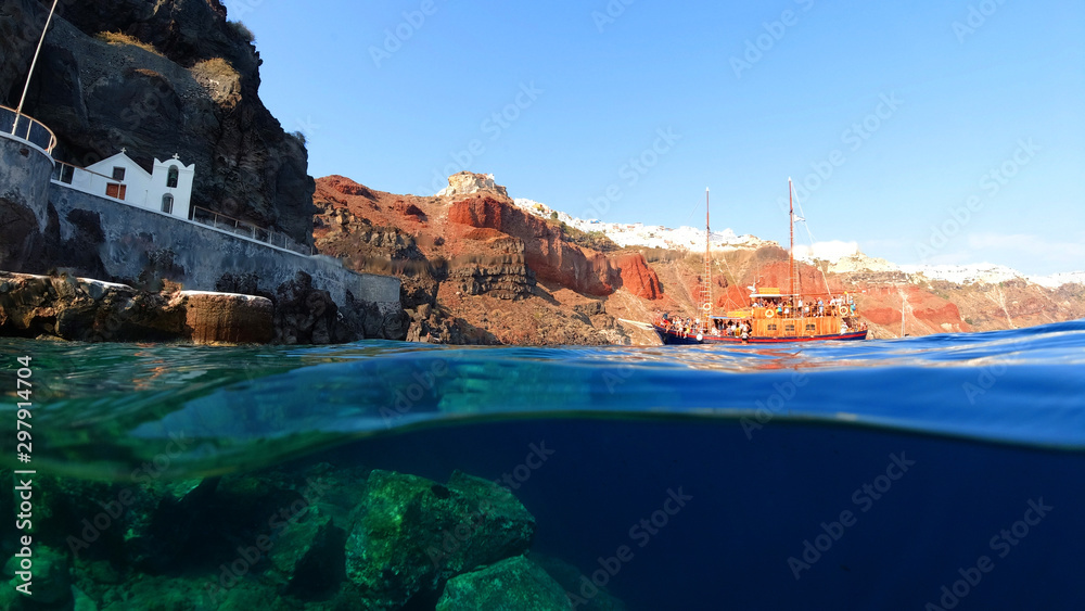Underwater and sea level photo of iconic islet and church of Agios Nikolaos below iconic village of Oia, Santorini island, Cyclades, Greece