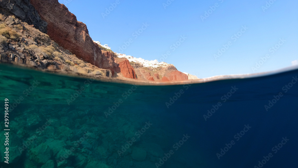 Underwater and sea level photo of fisherman in bay of Ammoudi below famous village of Oia, Santorini island, Cyclades, Greece