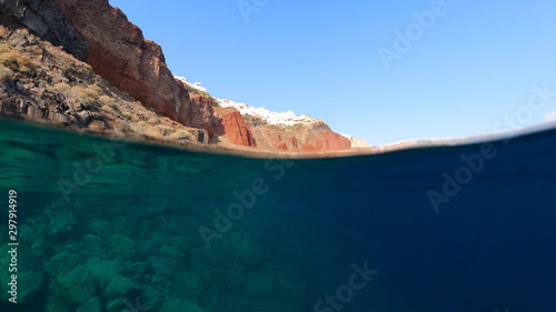 Underwater and sea level photo of fisherman in bay of Ammoudi below famous village of Oia  Santorini island  Cyclades  Greece