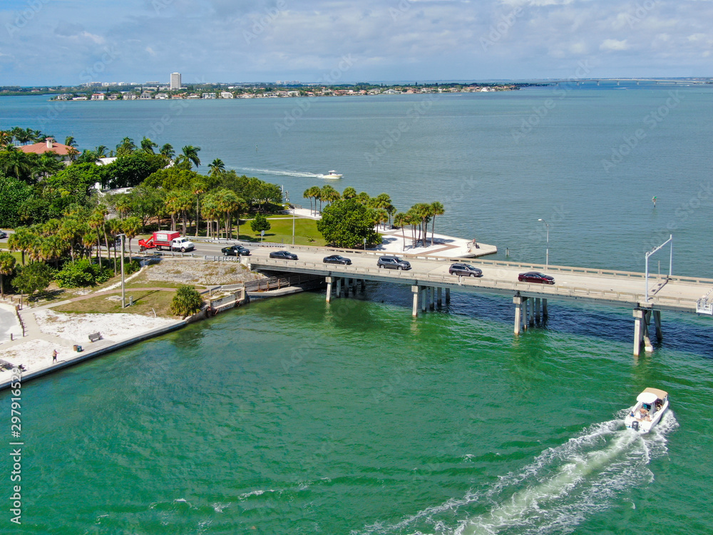 Aerial view of open street bridge crossing ocean with small boat and linking Island Bay and Sarasota, Florida, USA