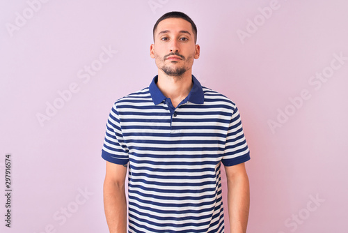 Young handsome man wearing nautical striped t-shirt over pink isolated background Relaxed with serious expression on face. Simple and natural looking at the camera.