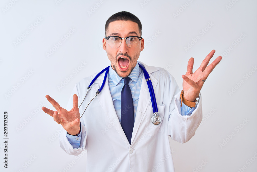 Young doctor man wearing stethoscope over isolated background celebrating mad and crazy for success with arms raised and closed eyes screaming excited. Winner concept