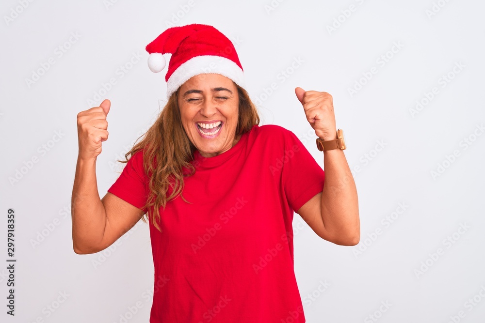 Middle age mature woman wearing christmas hat over isolated background excited for success with arms raised and eyes closed celebrating victory smiling. Winner concept. Middle age mature woman wearing christmas hat over isolated background excited for success with arms raised and eyes closed celebrating victory smiling. Winner concept.