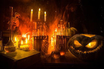 Halloween still-life background with different elements on dark toned foggy background. Selective focus
