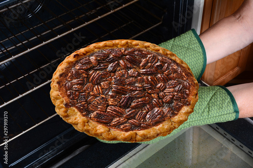 Konstfotografi Closeup of a woman taking a fresh baked Pecan Pie from the oven